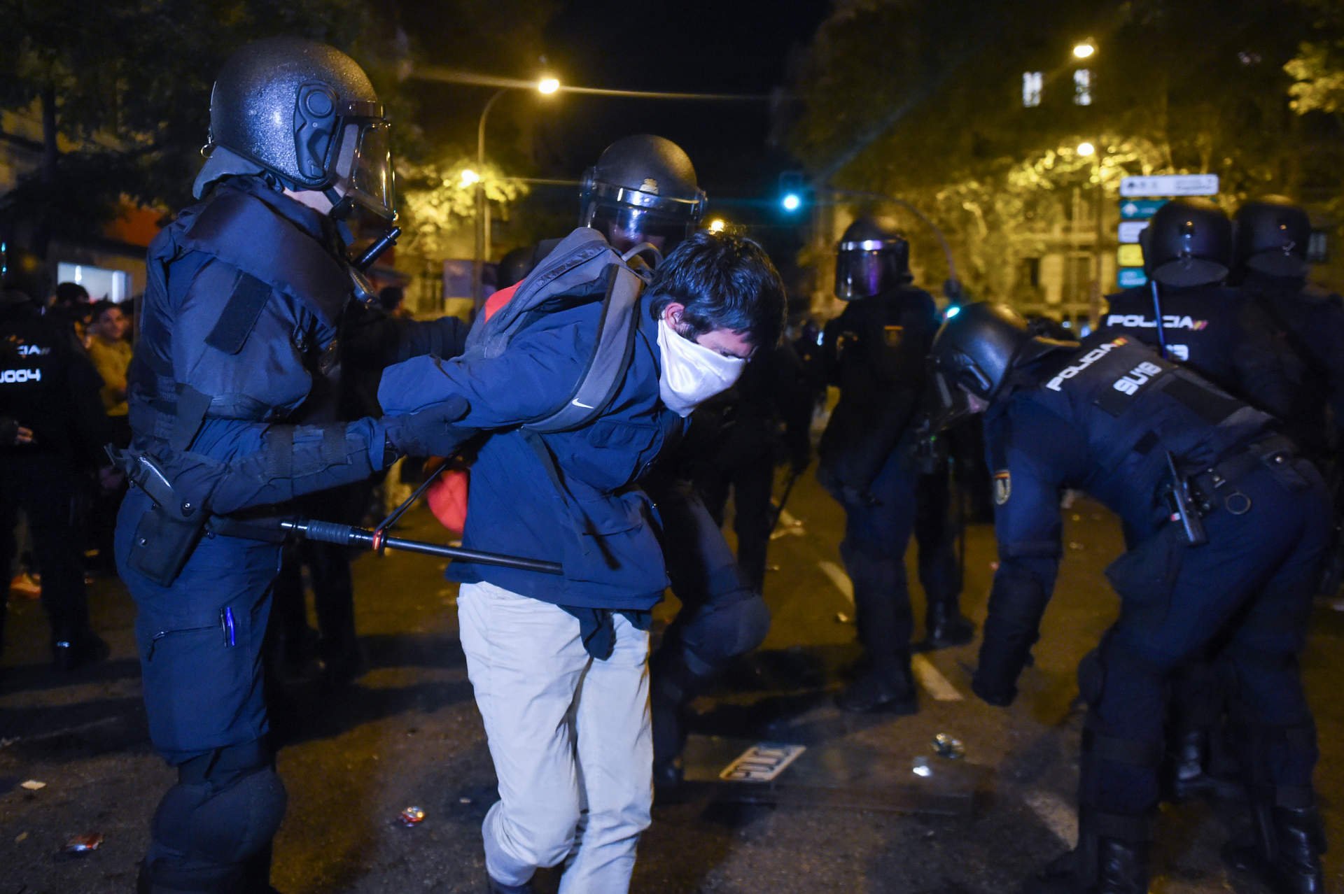 Un joven embozado es detenido por varios agentes de policía, durante una manifestación contra la amnistía frente a la sede del PSOE en Ferraz, a 18 de noviembre de 2023, en Madrid.