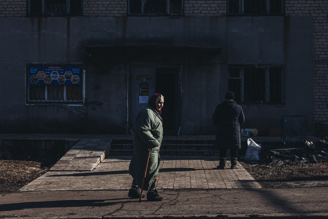 Una mujer mayor camina frente a un edificio bombardeado el pasado de 21 febrero, a 23 de febrero de 2022, en Novoluhans'ke, Oblast de Donetsk (Ucrania).