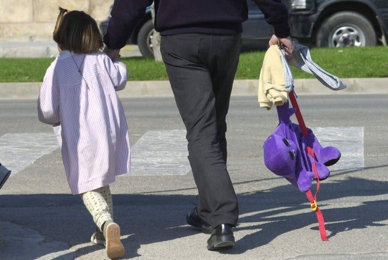 Un padre lleva a su hija al colegio. 