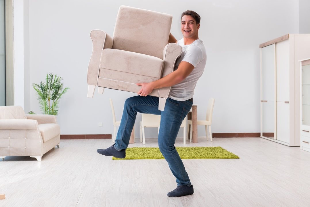 Un hombre moviendo un mueble.