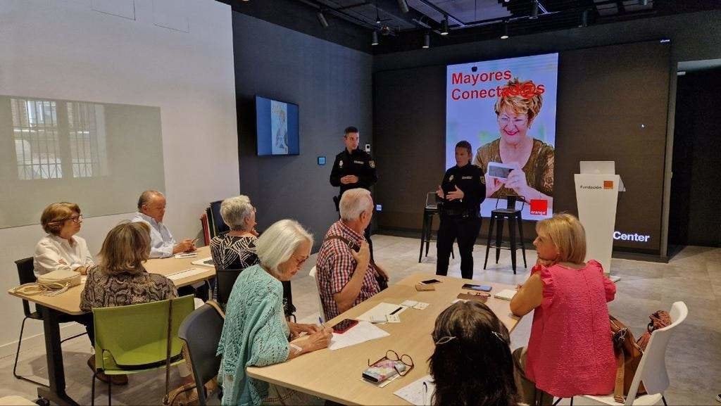 Agentes de la Policía Nacional imparten en el Orange Digital Center en Madrid el curso "Seguro con tu móvil" para romper la brecha digital entre las personas mayores.