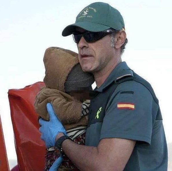 Un miembro de la Guardia Civil sostiene a un bebé rescatado.