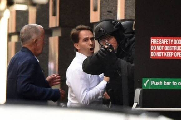 Un polic&iacute;a australiano protege a dos rehenes liberados.