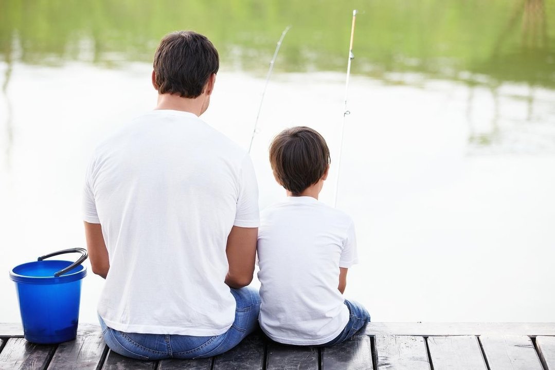 Padre e hijo pescando sentados en un embarcadero. 