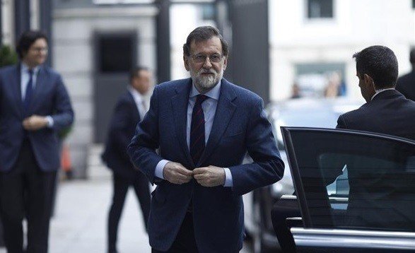Mariano Rajoy, saliendo del coche oficial junto a un escolta.