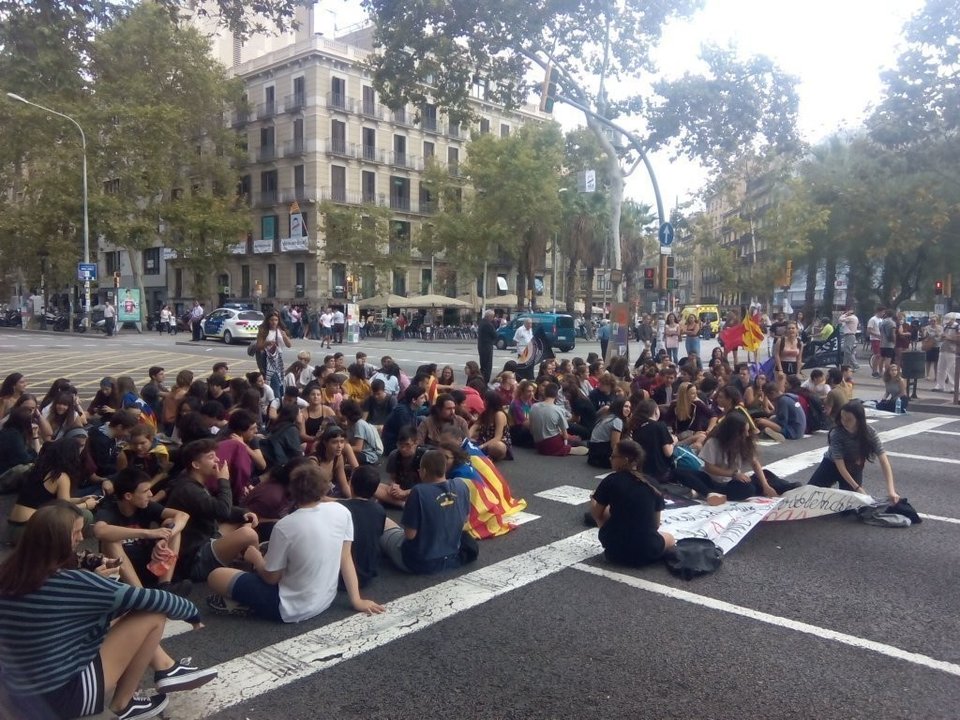 Estudiantes se sientan en la calzada de la Gran Vía de Barcelona para cortar el tráfico.