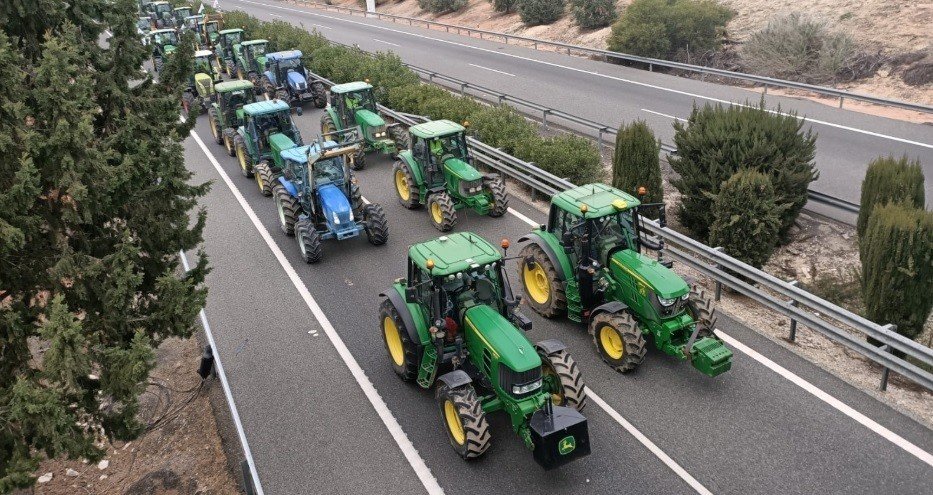 Agricultores bloquean una carretera con sus tractores.