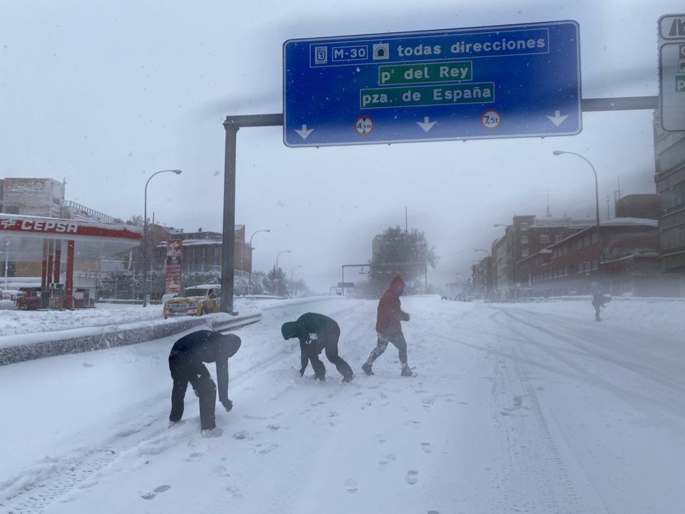 Tres personas juegan con copos de nieve sobre la calzada de la M30