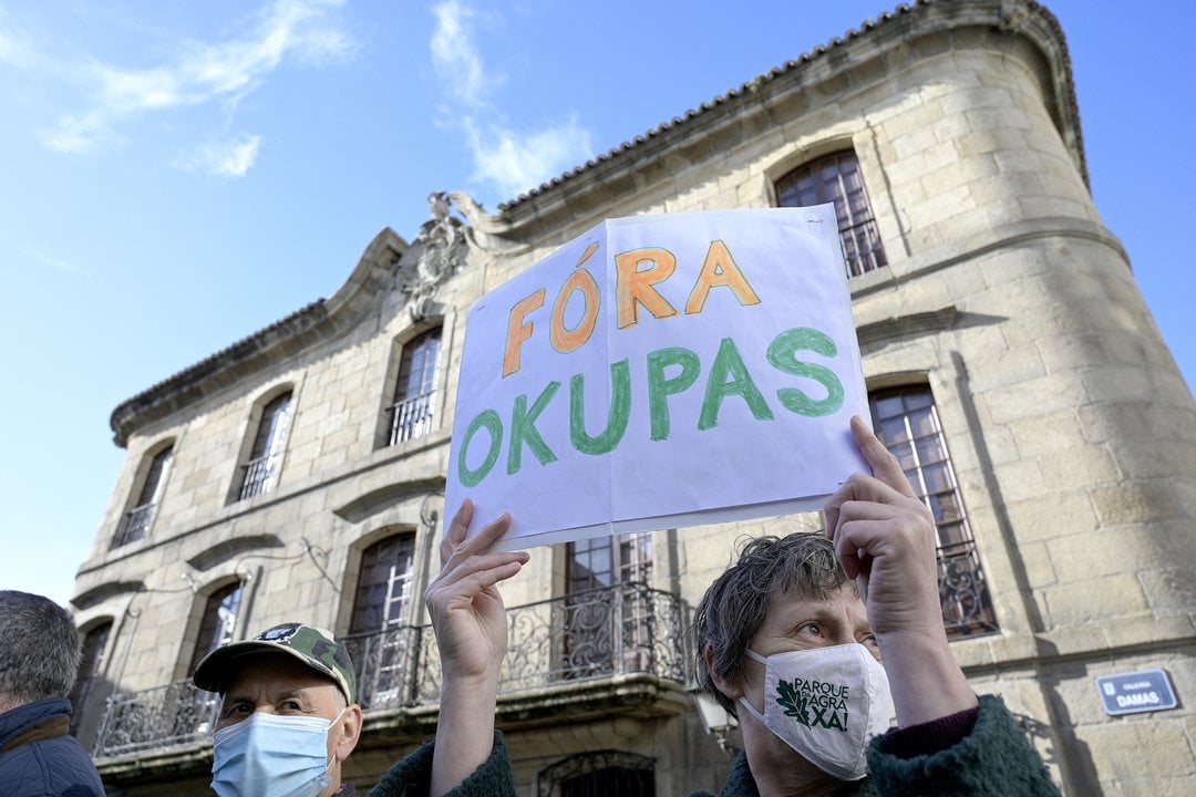 Una persona sostiene un cartel donde se puede leer "Fuera okupas" ante la Casa Cornide. Foto: M. Dylan / Europa Press.