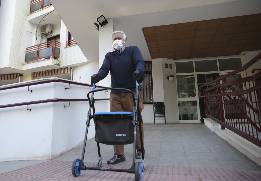 Un anciano sale de un centro residencial para mayores, durante el segundo día en el que los ancianos pueden salir a pasear.