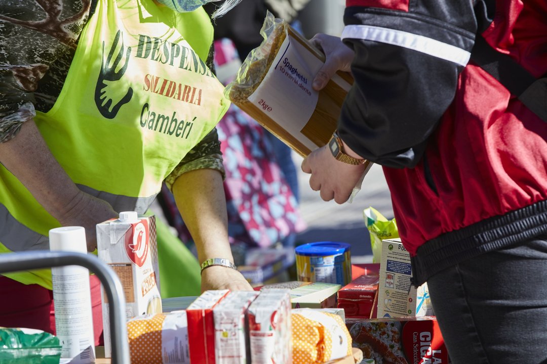 Varios miembros de la Despensa Solidaria de Chamberí reparte alimentos a familias vulnerables en la Plaza de Chamberí frente a las puertas de la Junta de Distrito, en Madrid (España), a 13 de marzo de 2021.