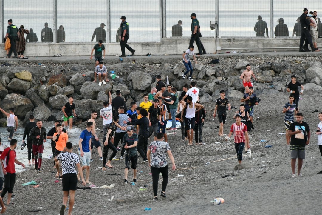 Personas migrantes caminan por la playa del Tarajal, a 17 de mayo de 2021, en Ceuta.