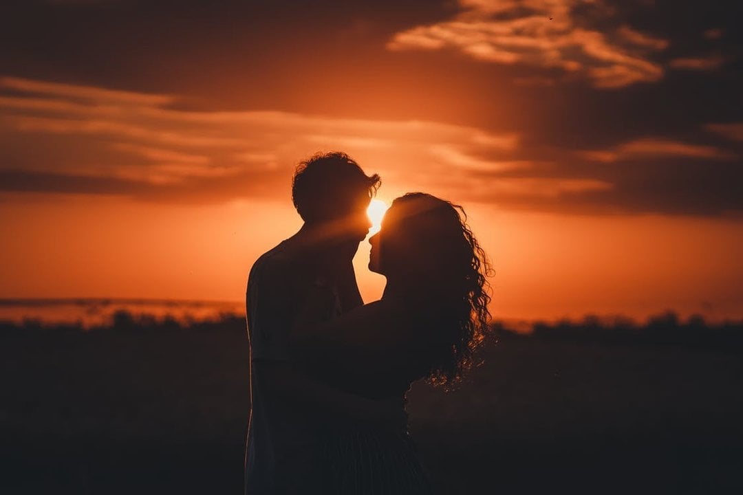 Una joven pareja delante de una puesta de sol.