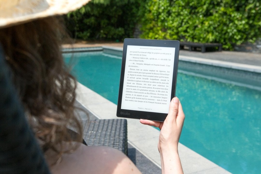Una persona leyendo un ebook junto a una piscina