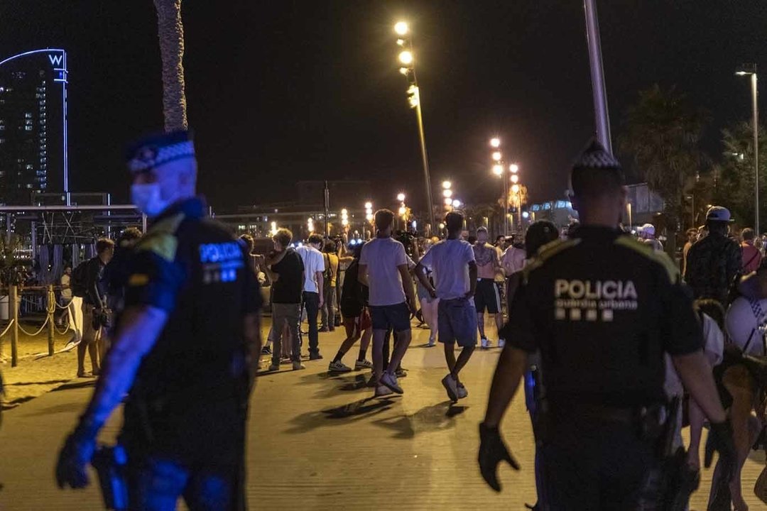 Varios agentes de la Guardia Urbana y jóvenes abandonando la playa de la Barceloneta. 17/7/2021