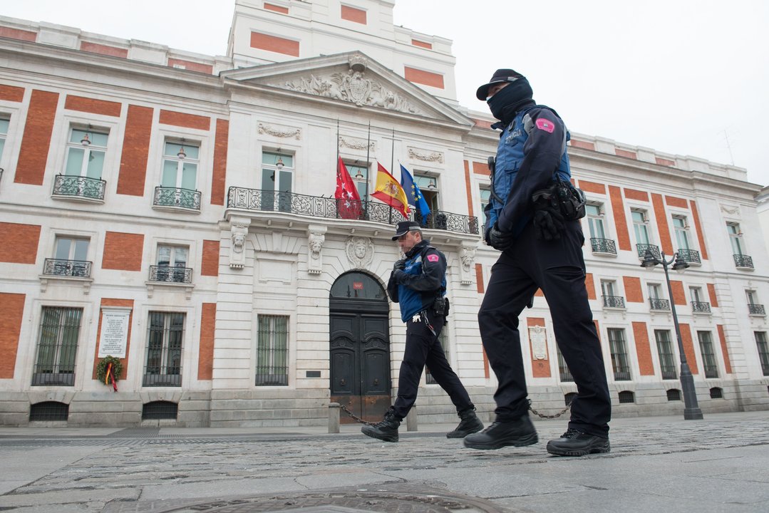 Dos agentes de la Policía Municipal caminan junto a la Real Casa de Correos, sede de la Comunidad de Madrid.