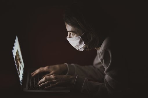 Una persona con mascarilla trabaja ante un ordenador.