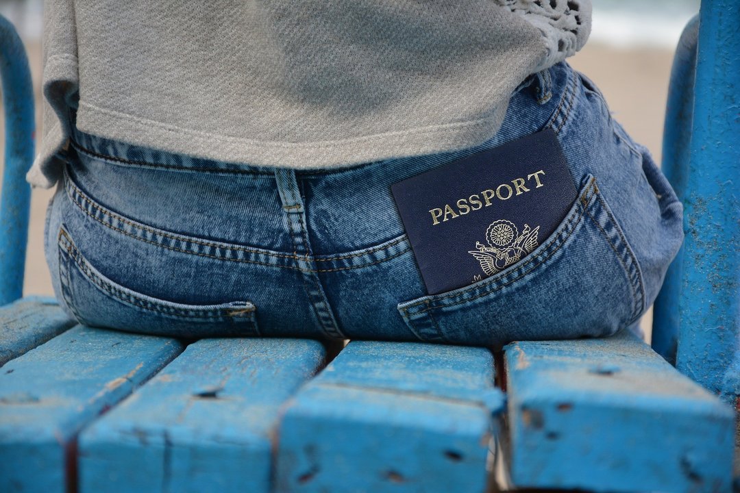Una persona con un pasaporte en el bolsillo trasero del pantalón.