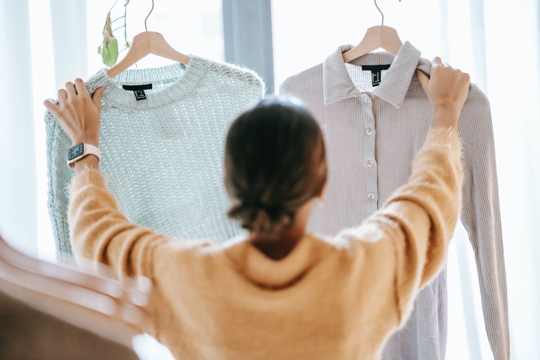 Una mujer levanta dos prendas de ropa.
