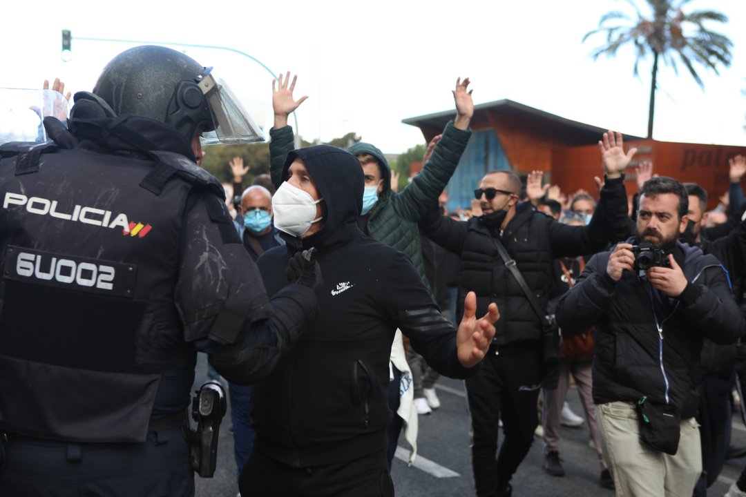 Manifestantes con las manos alzadas ante la policía que han intervenido durante los disturbios producidos por los estudiantes que se han manifestado en apoyo al sector del metal en Cádiz.