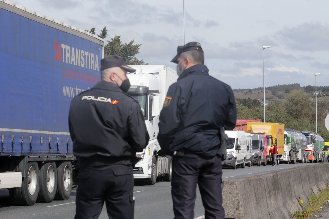 Agentes de Policía Nacional observan los camiones parados en el arcén en uno de los accesos al Polígono de O Ceao, en Lugo.