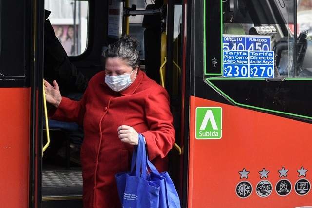 Una mujer con mascarilla baja de un autobús.