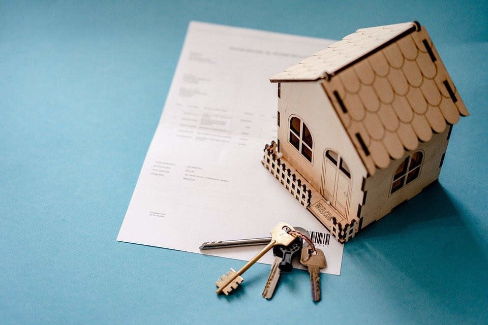 Llaves y un contrato de compra-venta de una vivienda y una casa en miniatura. Imagen de archivo