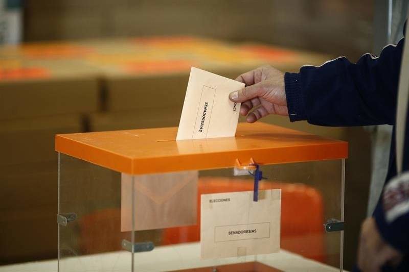 Una persona votando en una urna electoral.