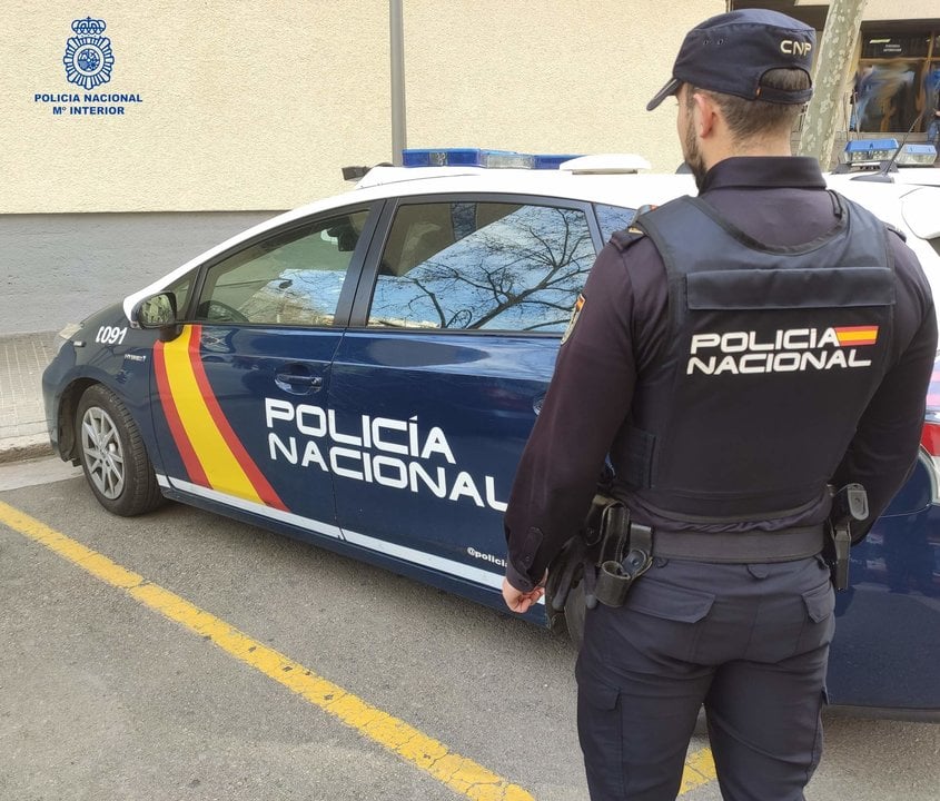 Un agente de la Policía Nacional en Palma de Mallorca junto al coche policial.