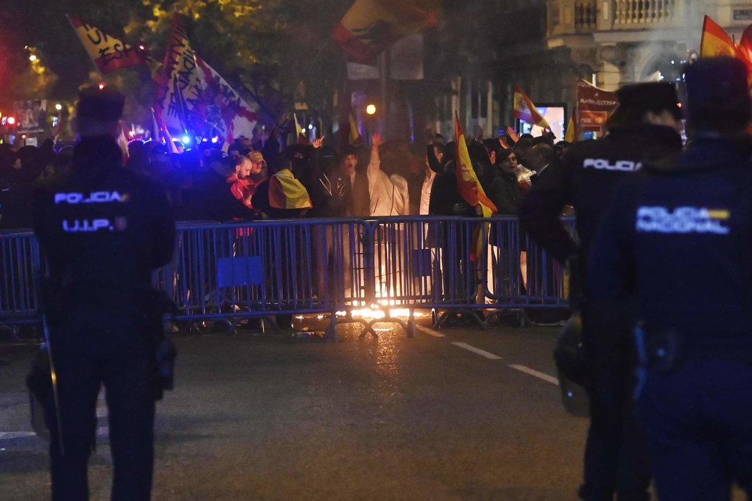 Varias personas queman una bandera estelada, durante la protesta convocada por el sindicato de Vox, en la calle Ferraz de Madrid.