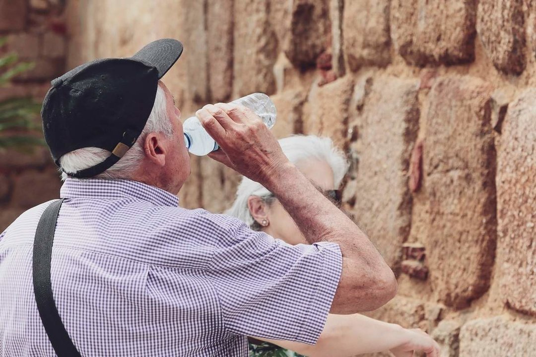 Un hombre mayor bebe agua de una botella en un día de intenso calor. Ayuntamiento de Mérida