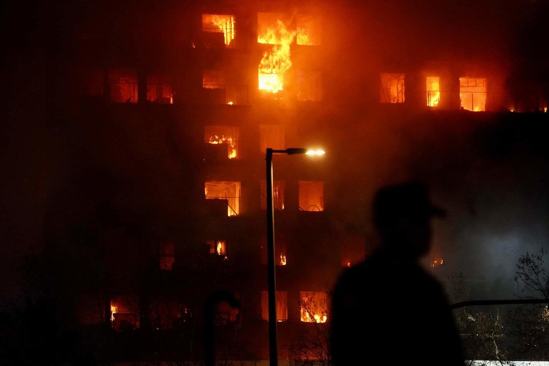 Un agente observa el edificio en llamas, en el barrio de Campanar.