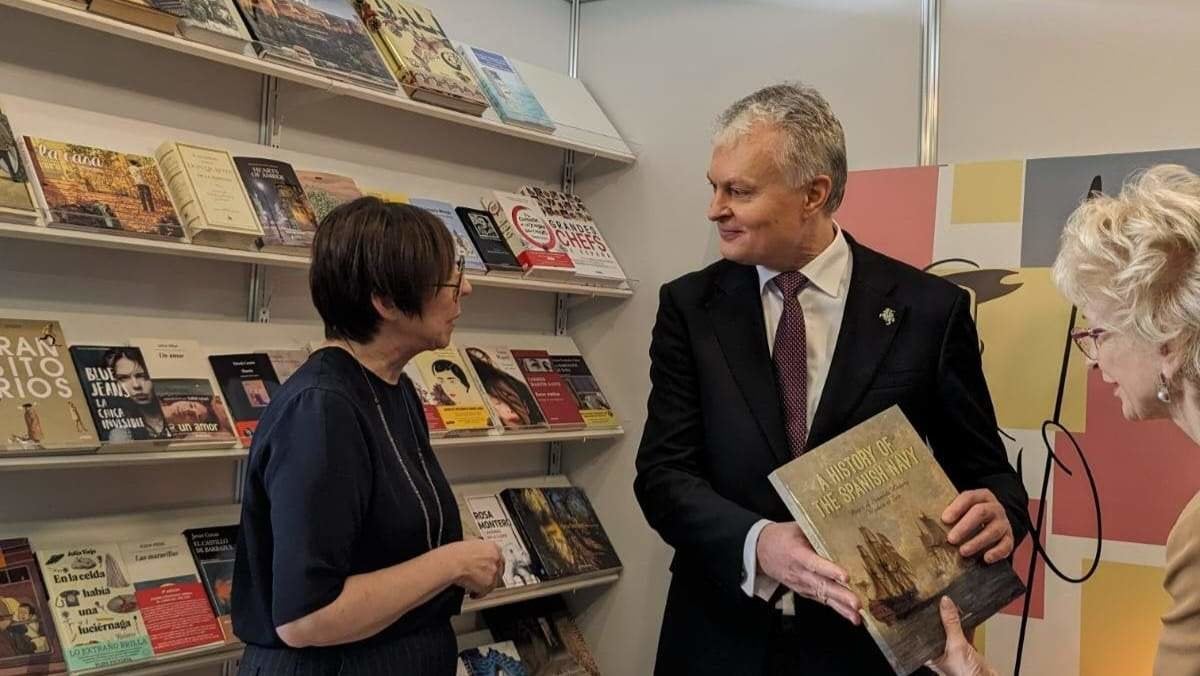 El presidente lituano Gitanas Nausėda conversa con la embajadora de España, Nieves Blanco, mientras sostiene en sus manos el libro "Una historia de la Armada Española"
