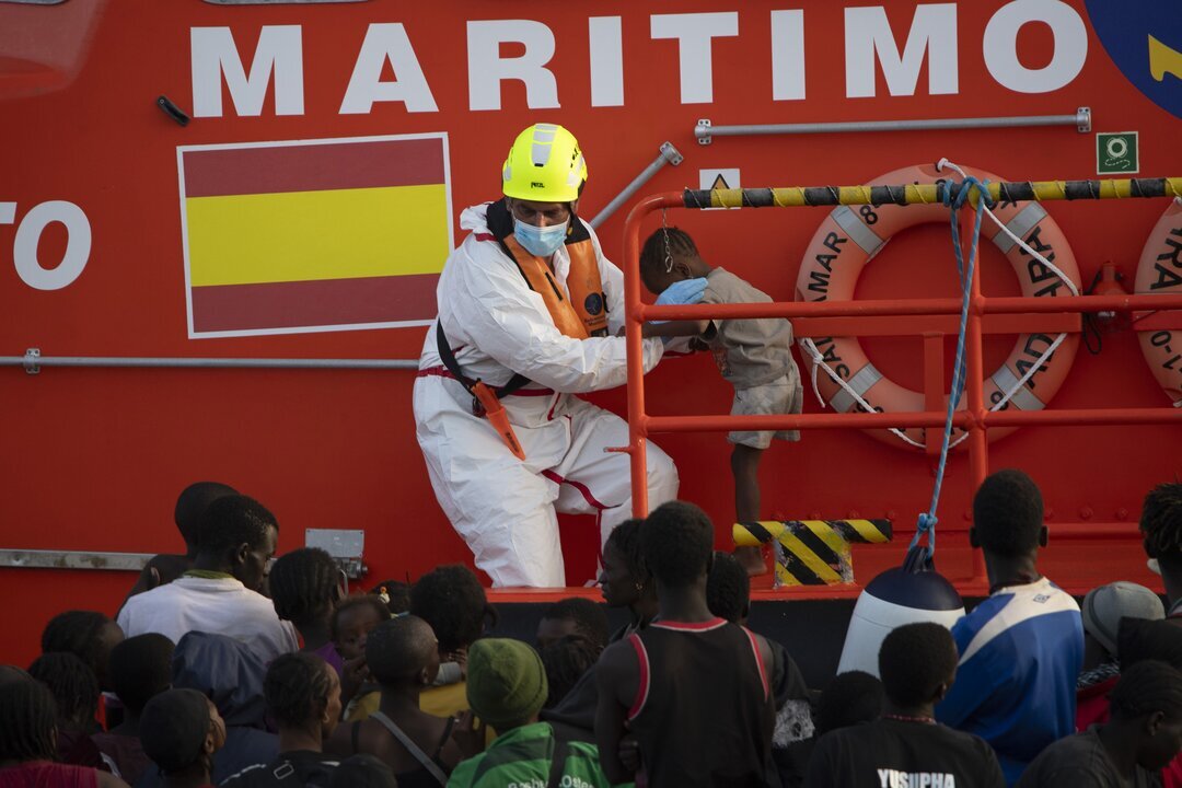 Una persona de Salvamento Mar&iacute;timo ayuda a un menor, en el Puerto de la Restinga.