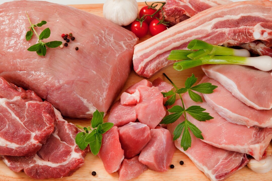Detail - different type of meat (pork steak, tenderloin, belly, neck, shoulder) decorated on a chopping board with garnish