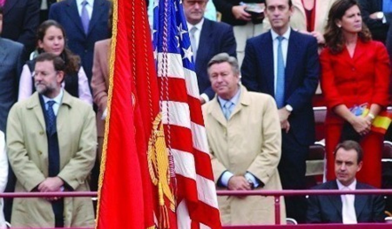 Zapatero sentado al paso de la bandera de USA.
