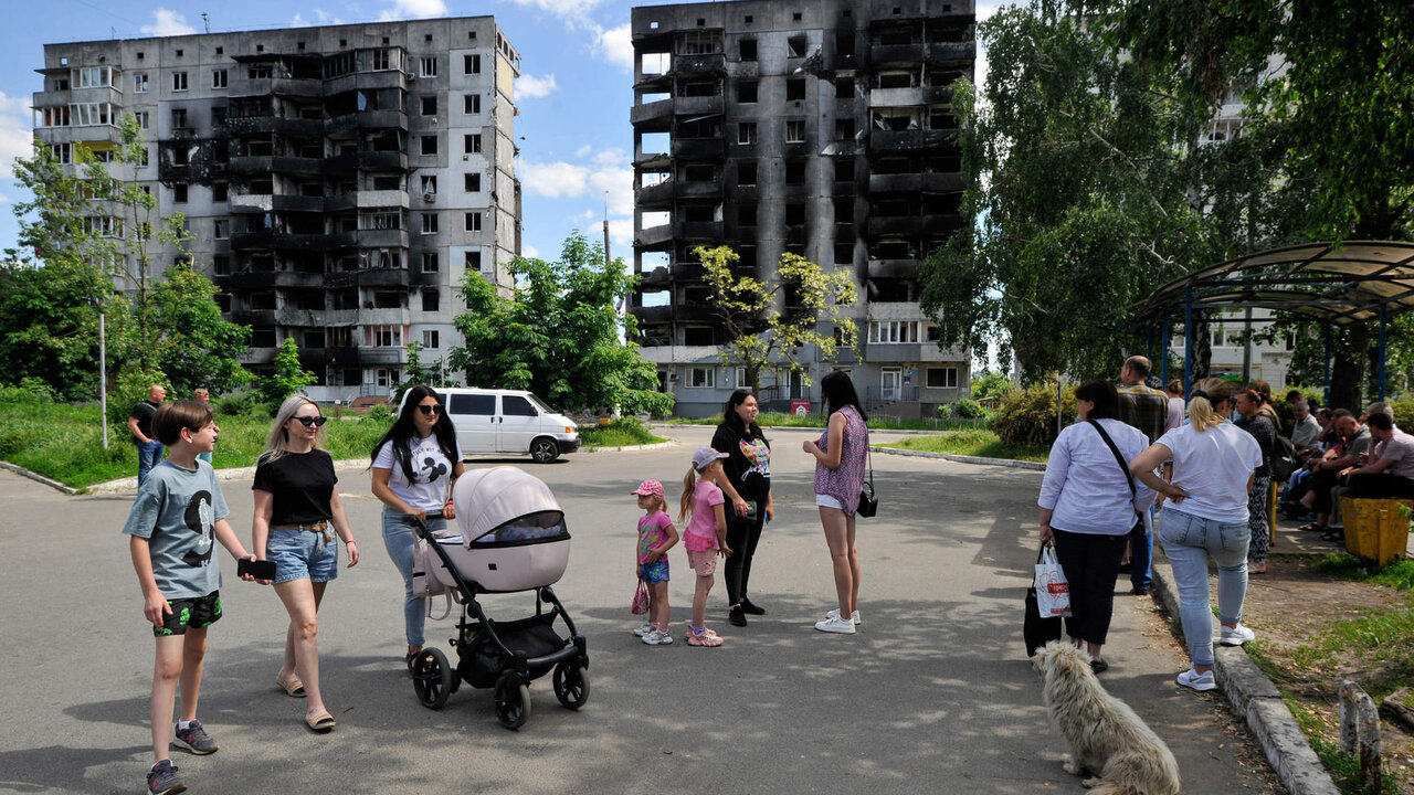People stand at a bus stop nearby destroyed residential area that was damaged as a result of the shelling of  the Russian army in the city of Borodyanka, northwest of the Ukrainian capital Kyiv.