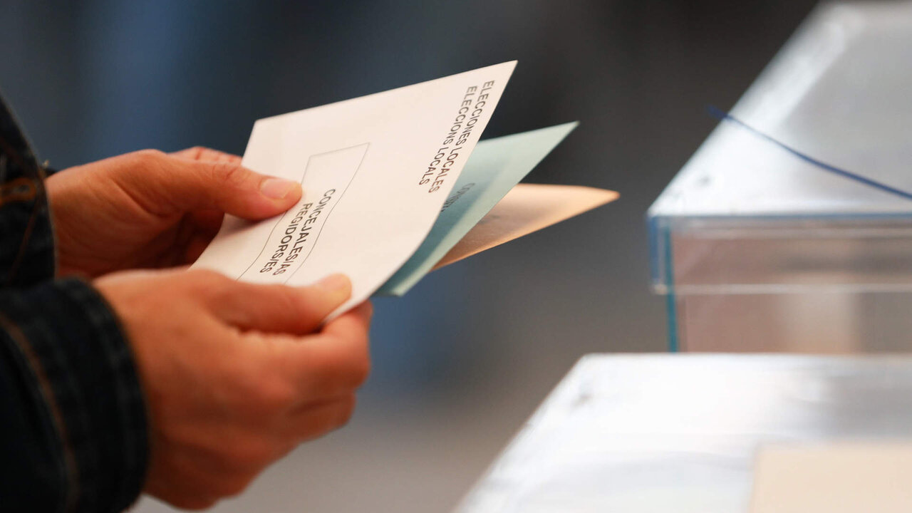 Una persona sostiene papeletas electorales frente a las urnas, a 28 de mayo de 2023, en Palma.