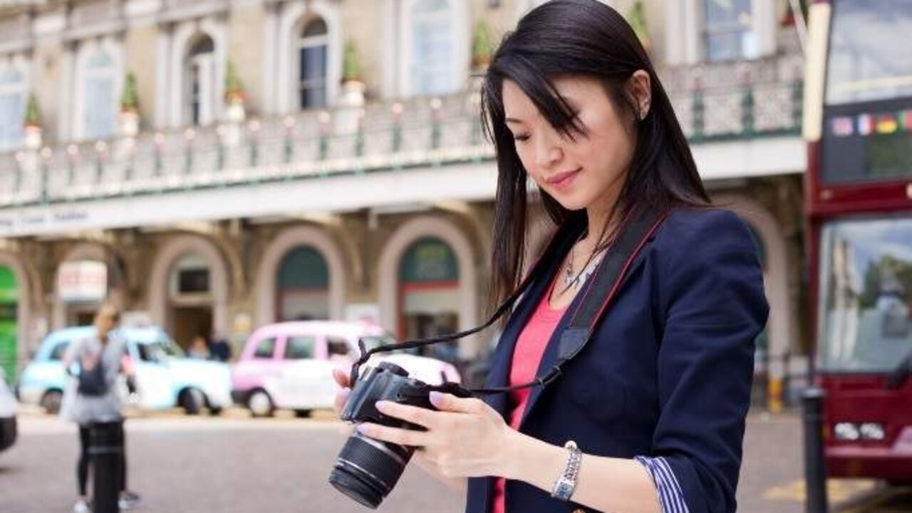 young chinese tourist looking through her photos on her camera.