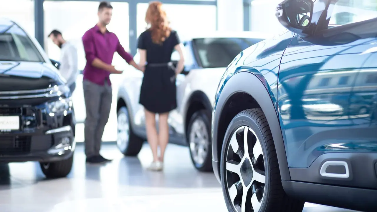 Low angle of exclusive car in a dealing salon with seller and buyer