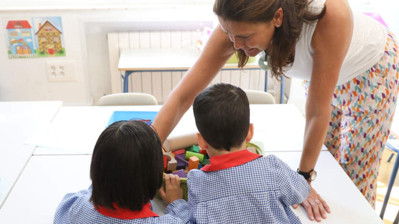 Una profesora ayuda a dos ni&ntilde;os durante una clase. Europa Press