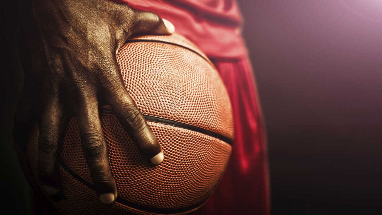 Hand tightly gripping basketball up close.