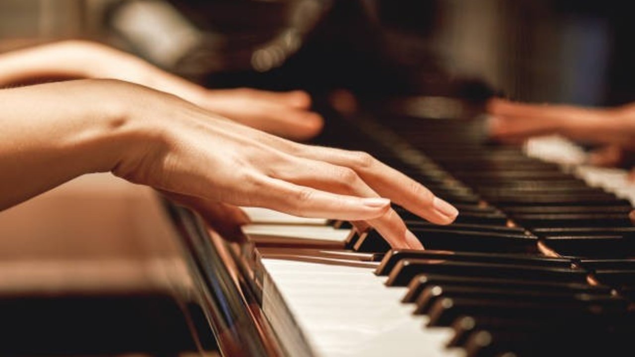 Favorite classical music...Close up view of gentle female hands playing a melody on piano while taking piano lessons. Musical instrument. Music education. Piano keyboard