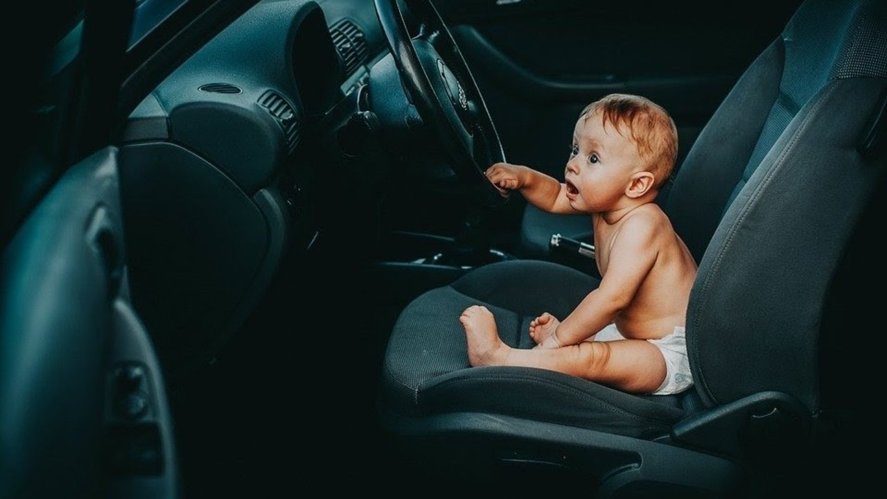Un niño sentado ante el volante de un coche.