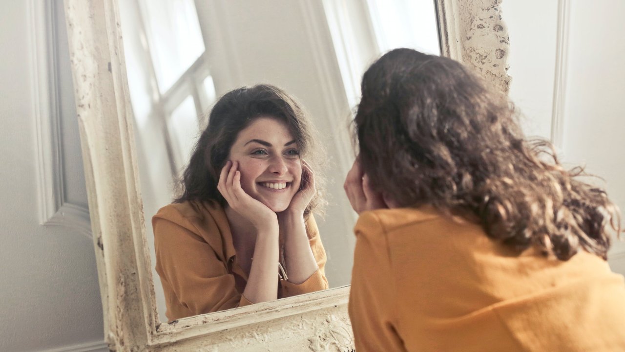 Una mujer mirándose en un espejo.
