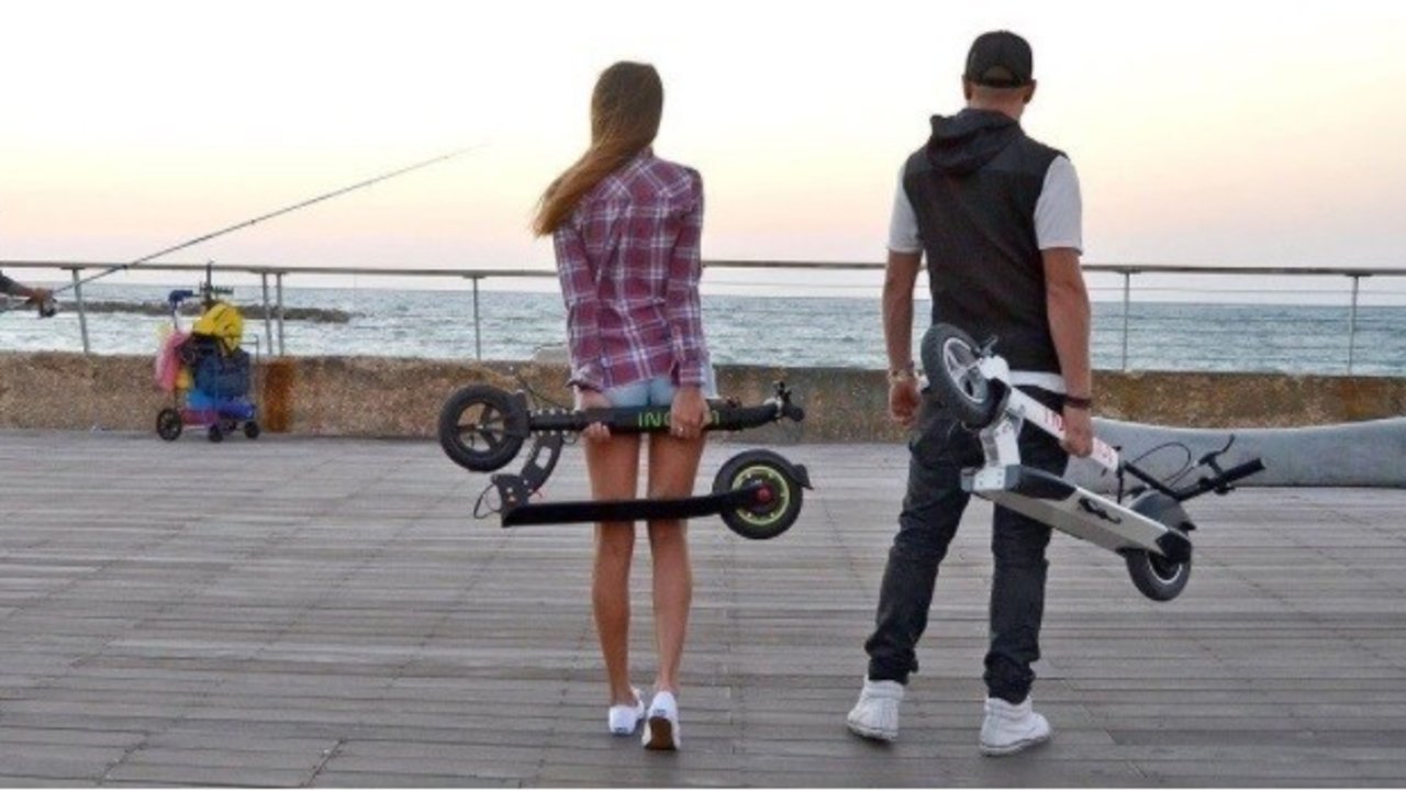 Una pareja con sus patinetes eléctricos.