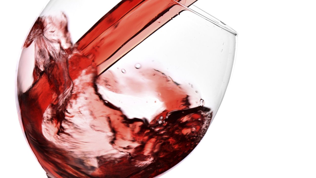Red wine pour into glass isolated over white background