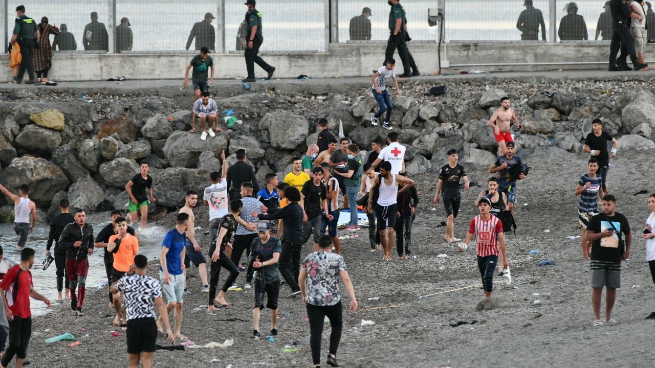 Personas migrantes caminan por la playa del Tarajal, a 17 de mayo de 2021, en Ceuta (España).