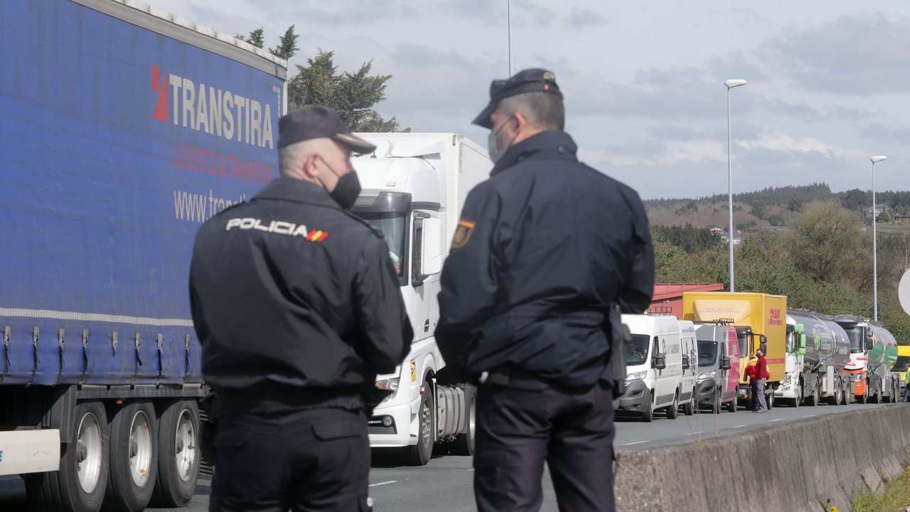 Agentes de Policía Nacional observan los camiones parados en el arcén en uno de los accesos al Polígono de O Ceao, en Lugo.