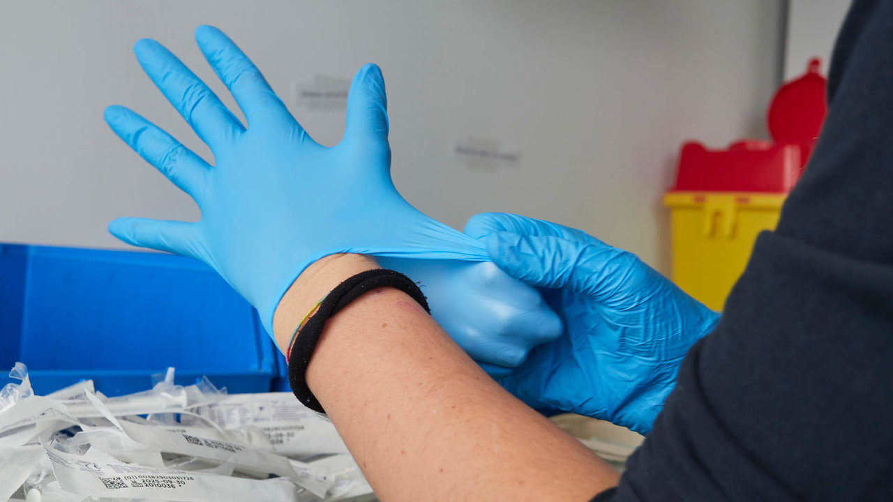 Una profesional sanitaria se pone guantes de nitrilo en un dispositivo de vacunación contra el Covid-19